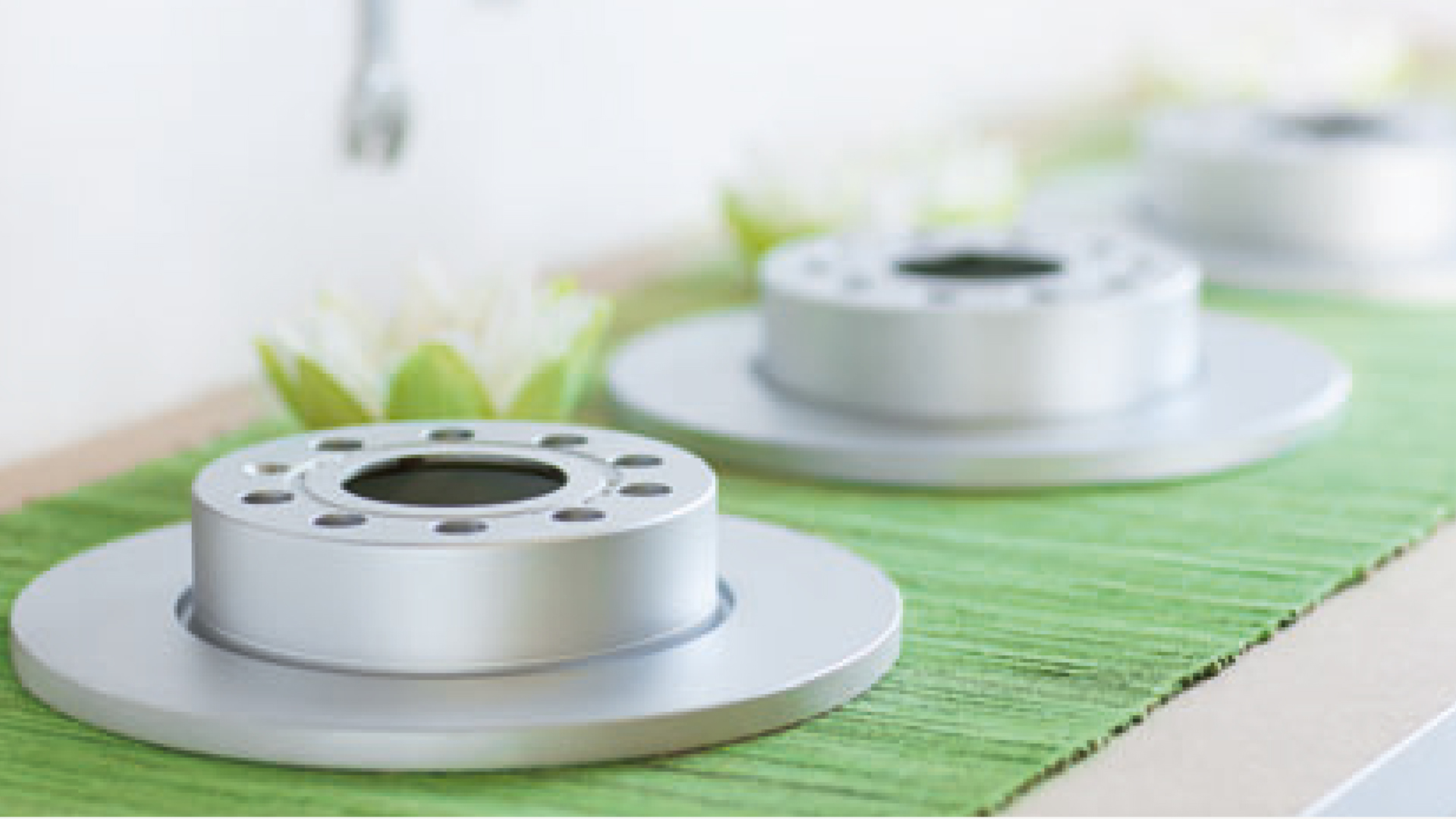 Bremsscheiben auf grünem Tuch und Seerosenblüten im Hintergrund